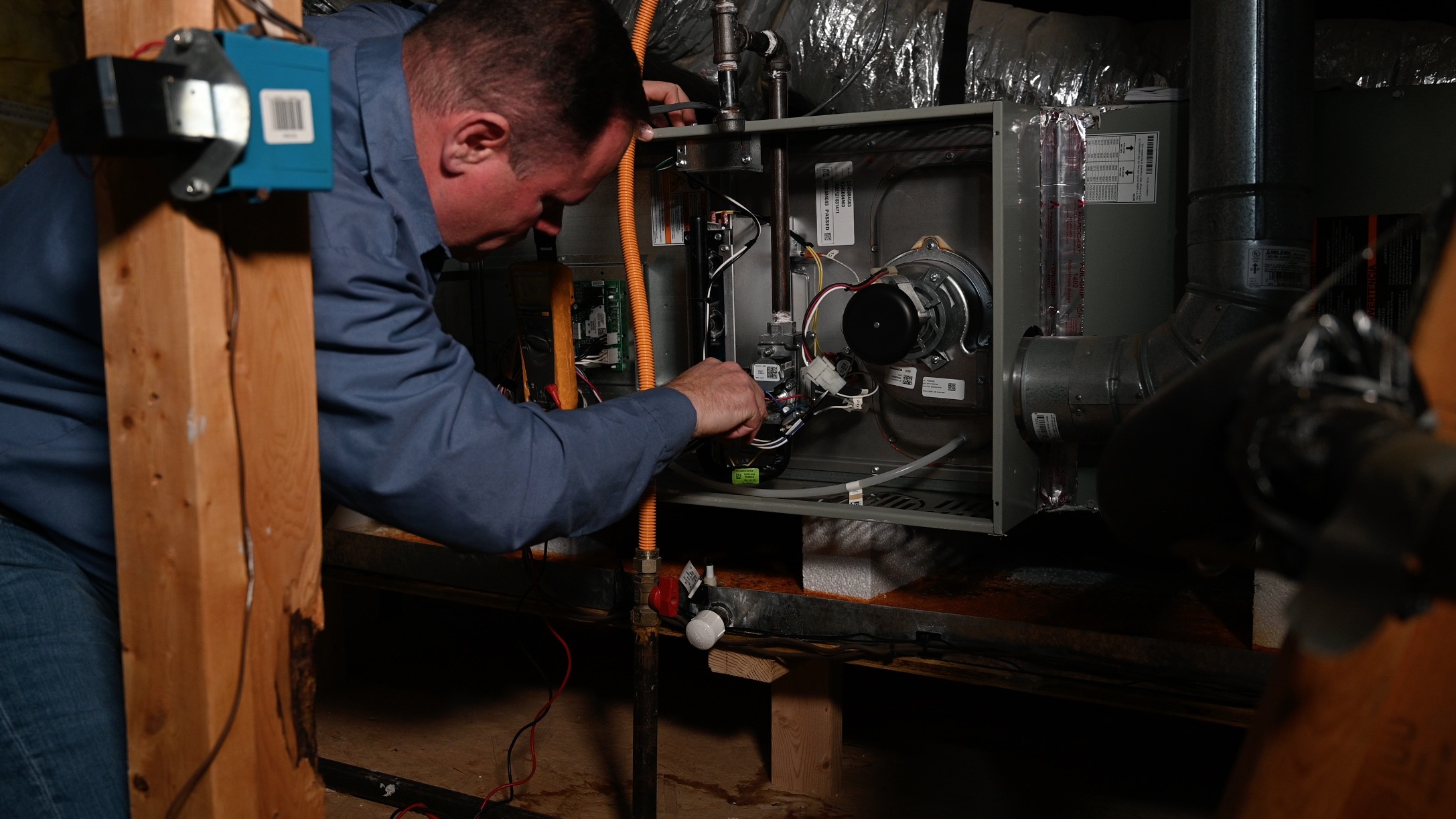HVAC Technician repairing a furnace in the attic.