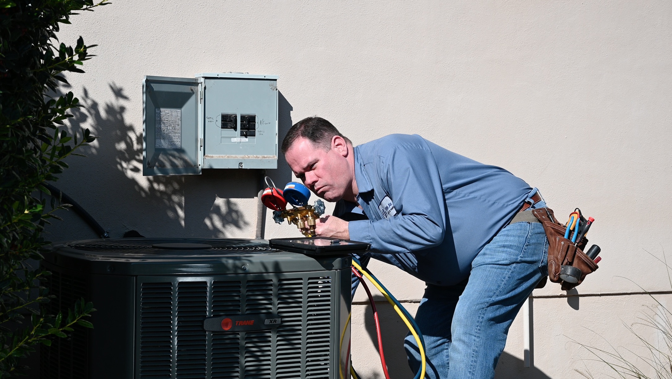 SM Air techinician checking an outdoor AC unit for issues.