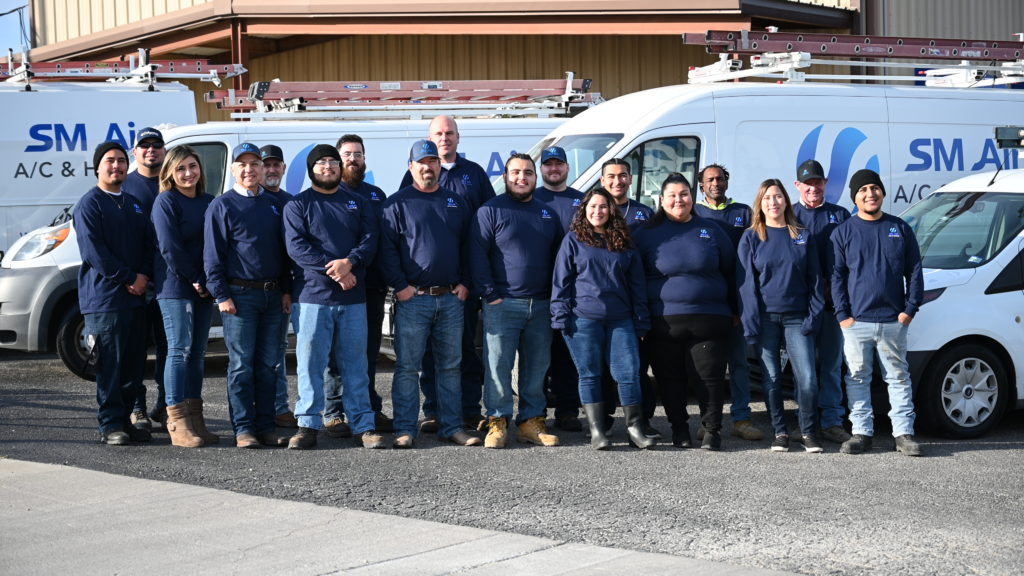 SM Air team with eighteen members standing in two lines with trucks behind them.