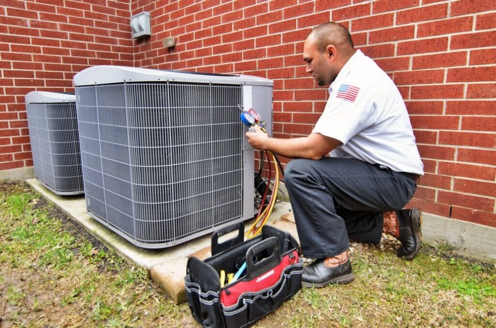SM Air tech in uniform checking on an AC condenser outside a home in Reedville, TX.