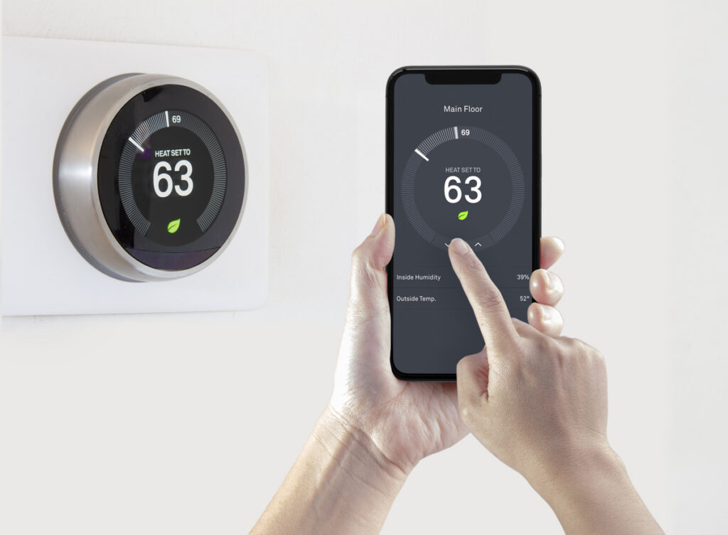 Homeowner using smartphone to adjust smart thermostat