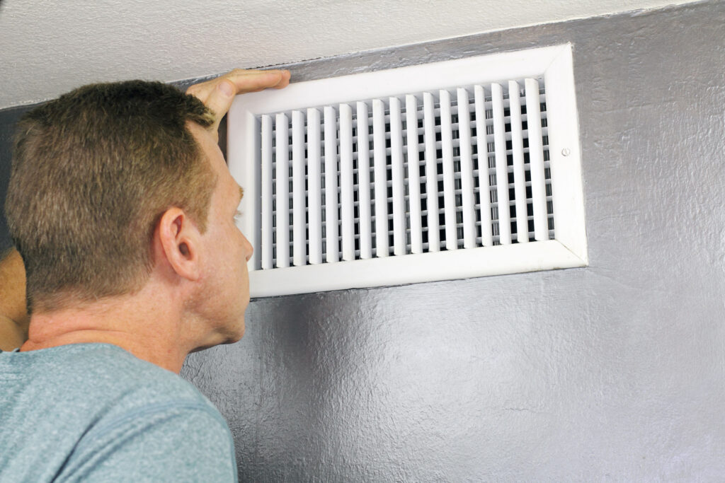 Homeowner looking into vent blowing hot air